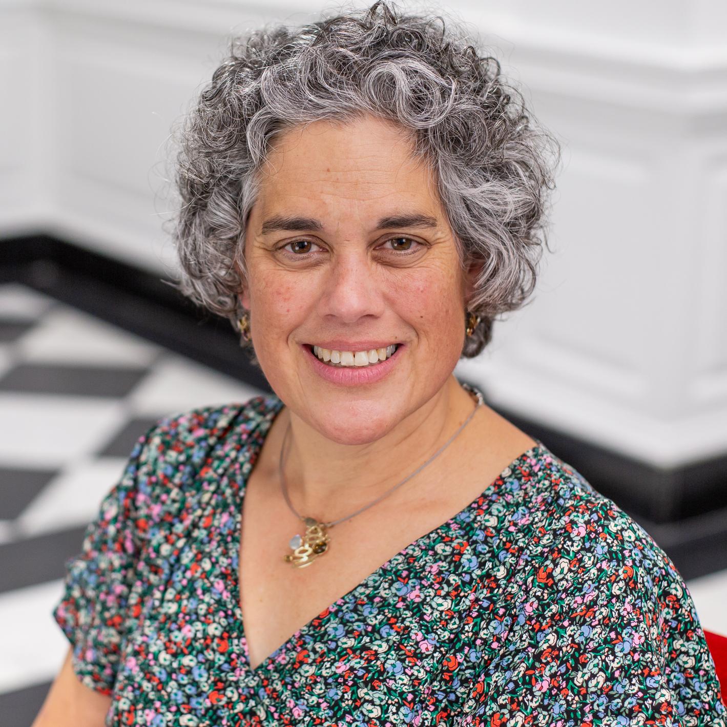 woman with short curly hair and a floral top 
