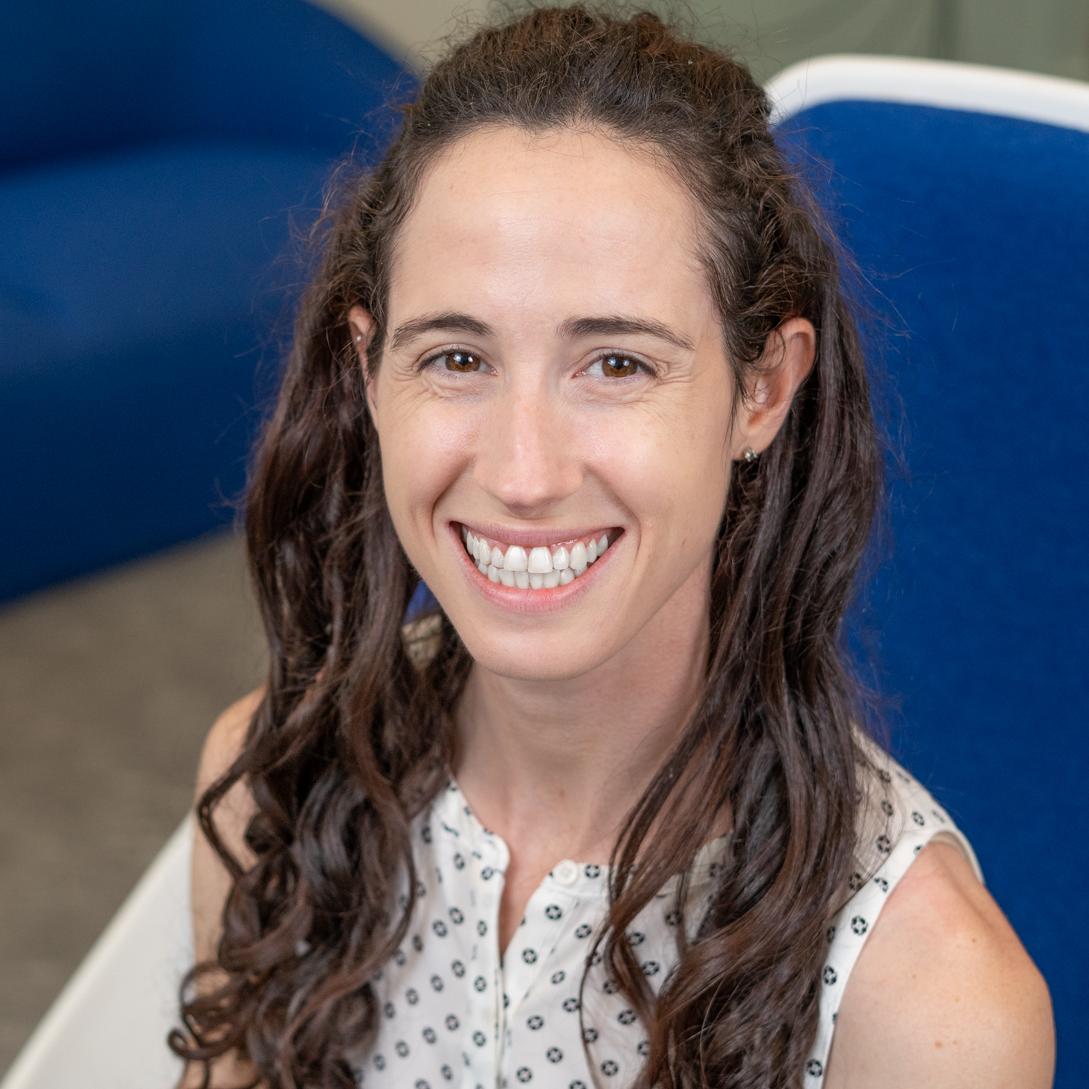 smiling woman with long brown hair sitting in a bright blue chair