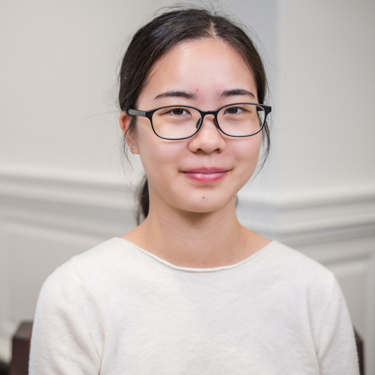portrait of a person wearing a white shirt and glasses