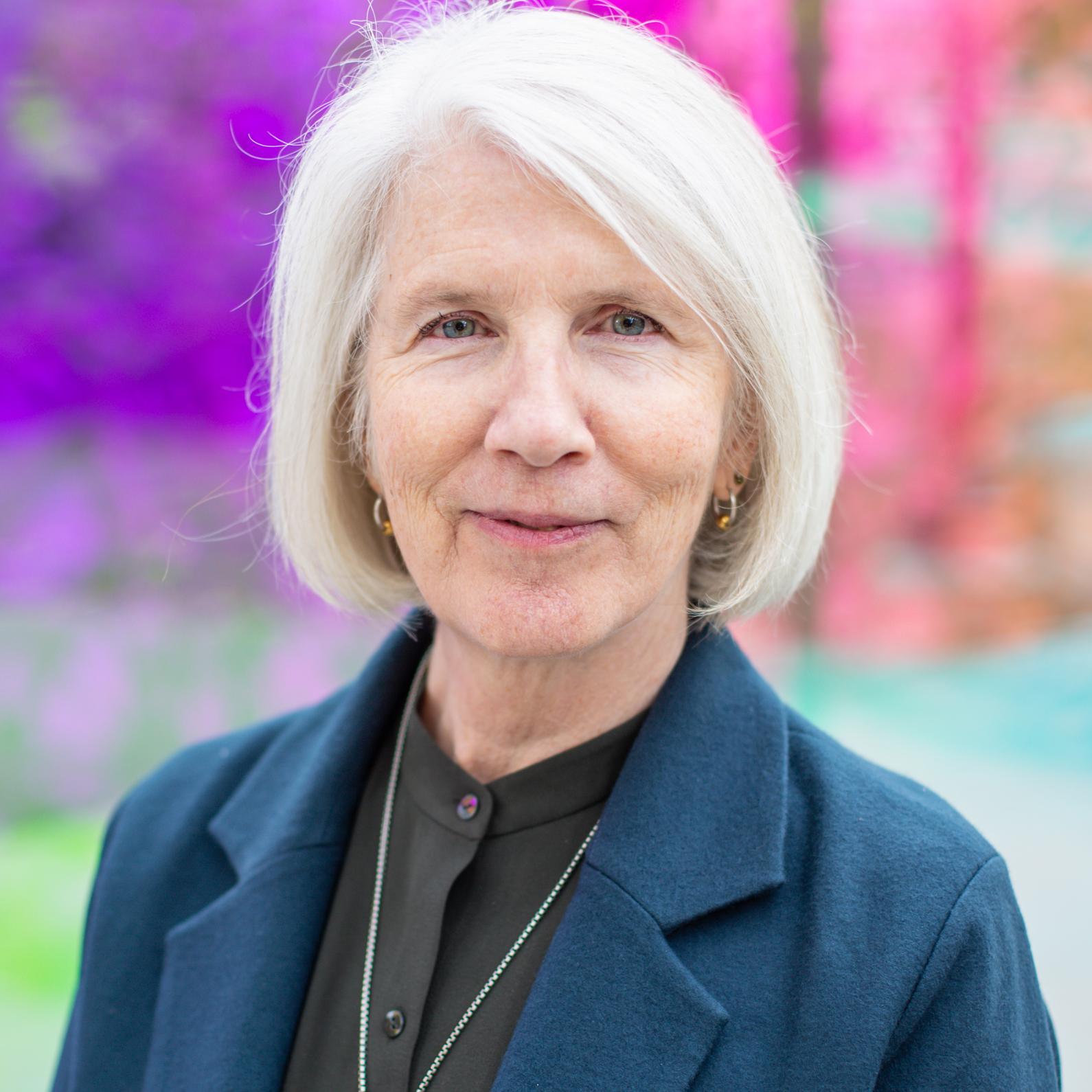 woman wearing a blue blazer and silver pendant necklace