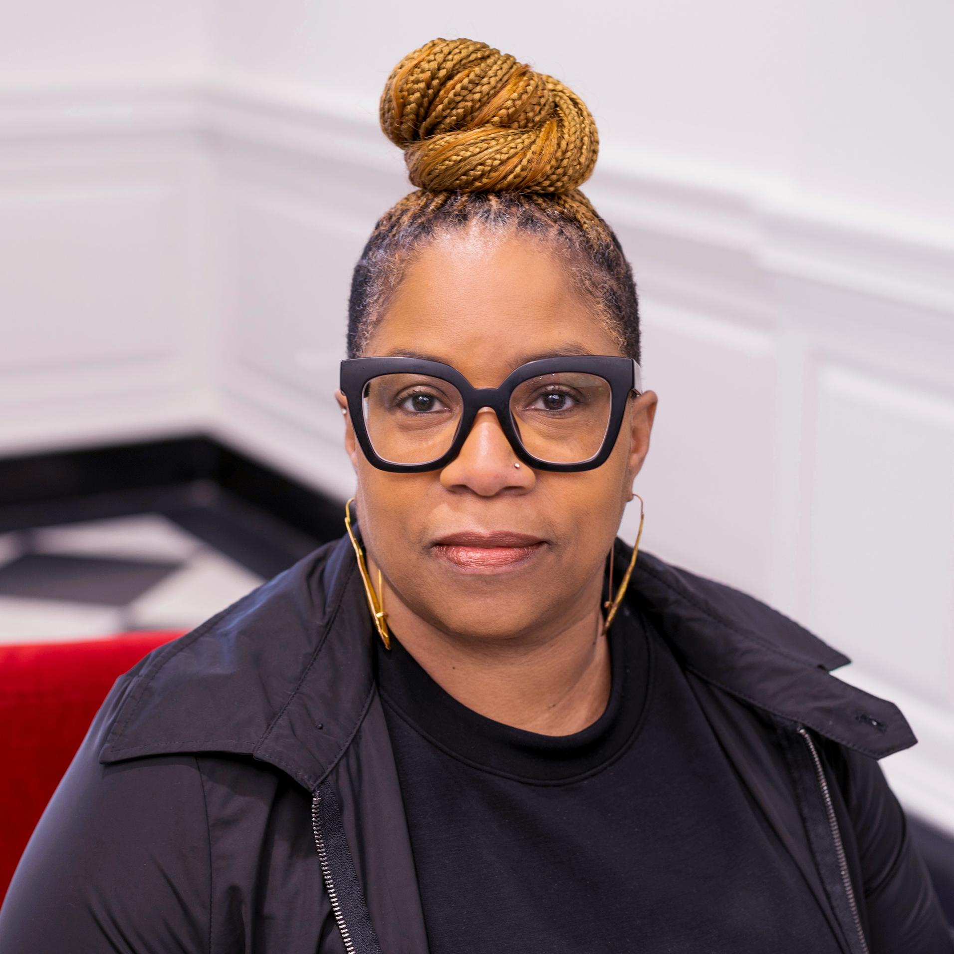 portrait of a woman in black framed glasses looking at the camera