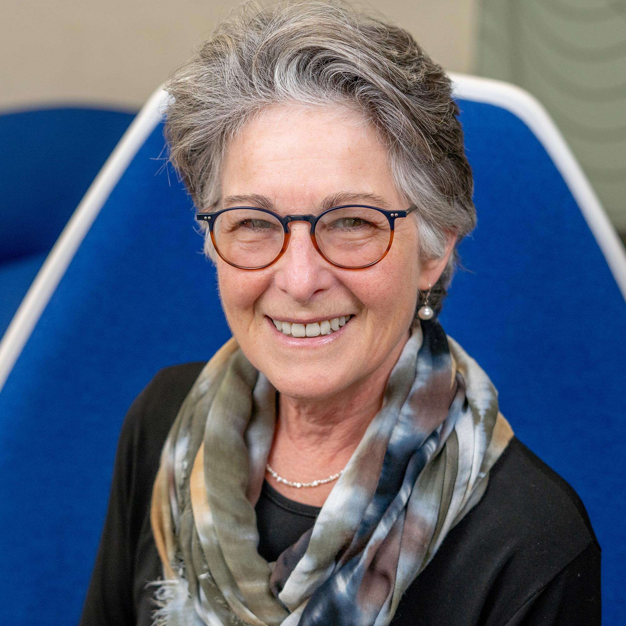 woman wearing glasses sitting in a blue chair