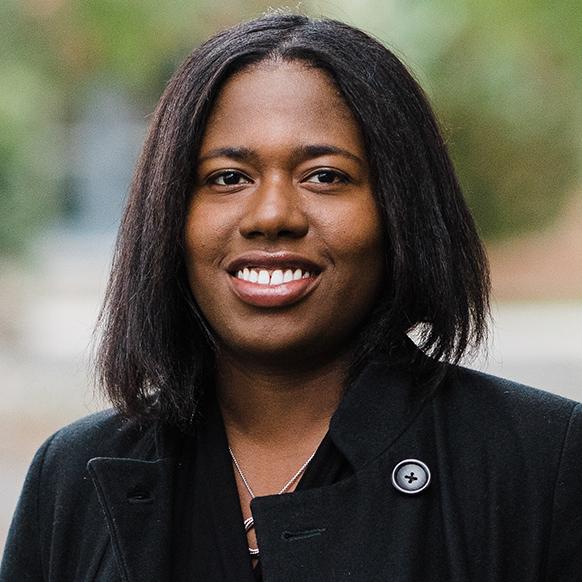 portrait of a woman wearing a dark coat standing in a garden