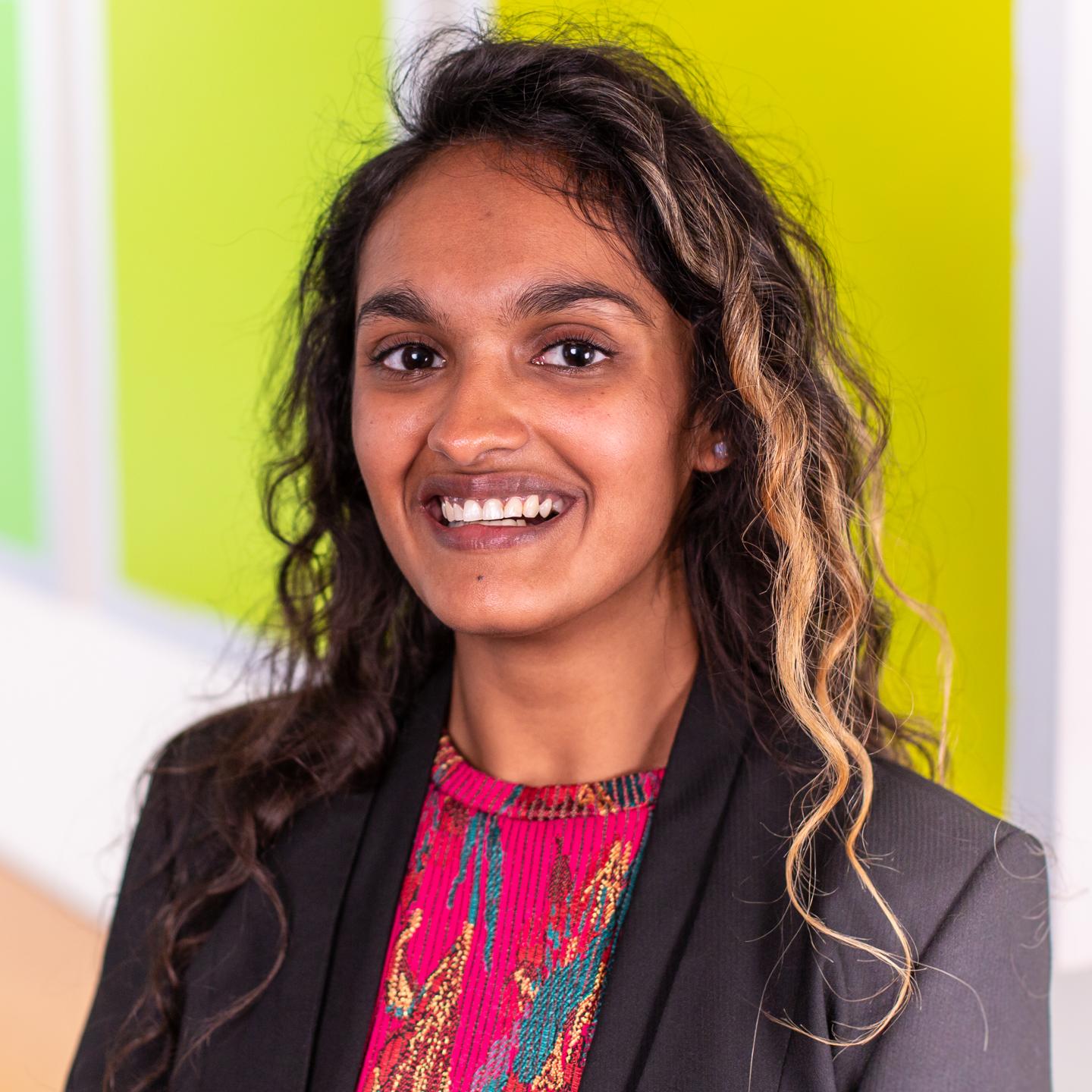woman with long curly hair standing in front of bright green wall panels