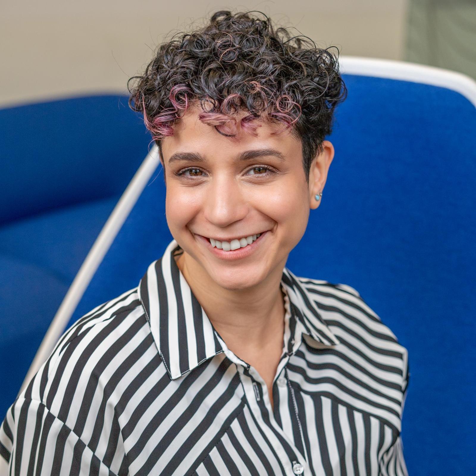 woman in a striped shirt sitting in a bright blue chair