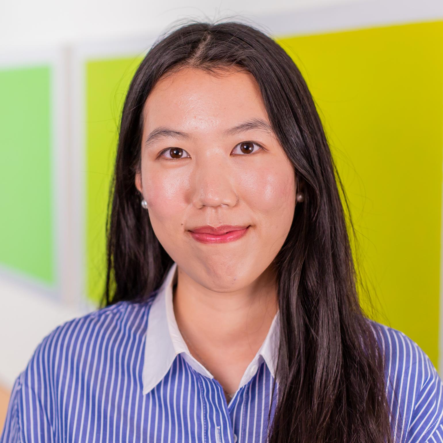 woman in a blue striped button down shirt standing in front of bright green wall panels