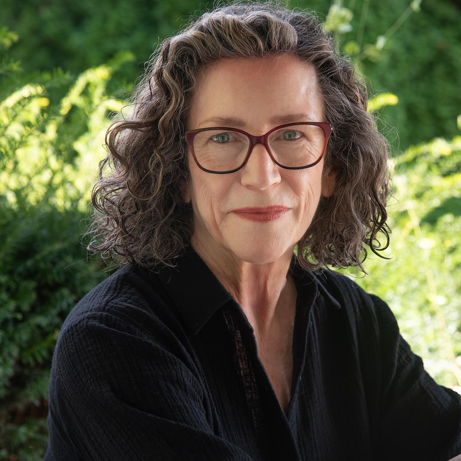 portrait of a woman with curly brown hair and glasses