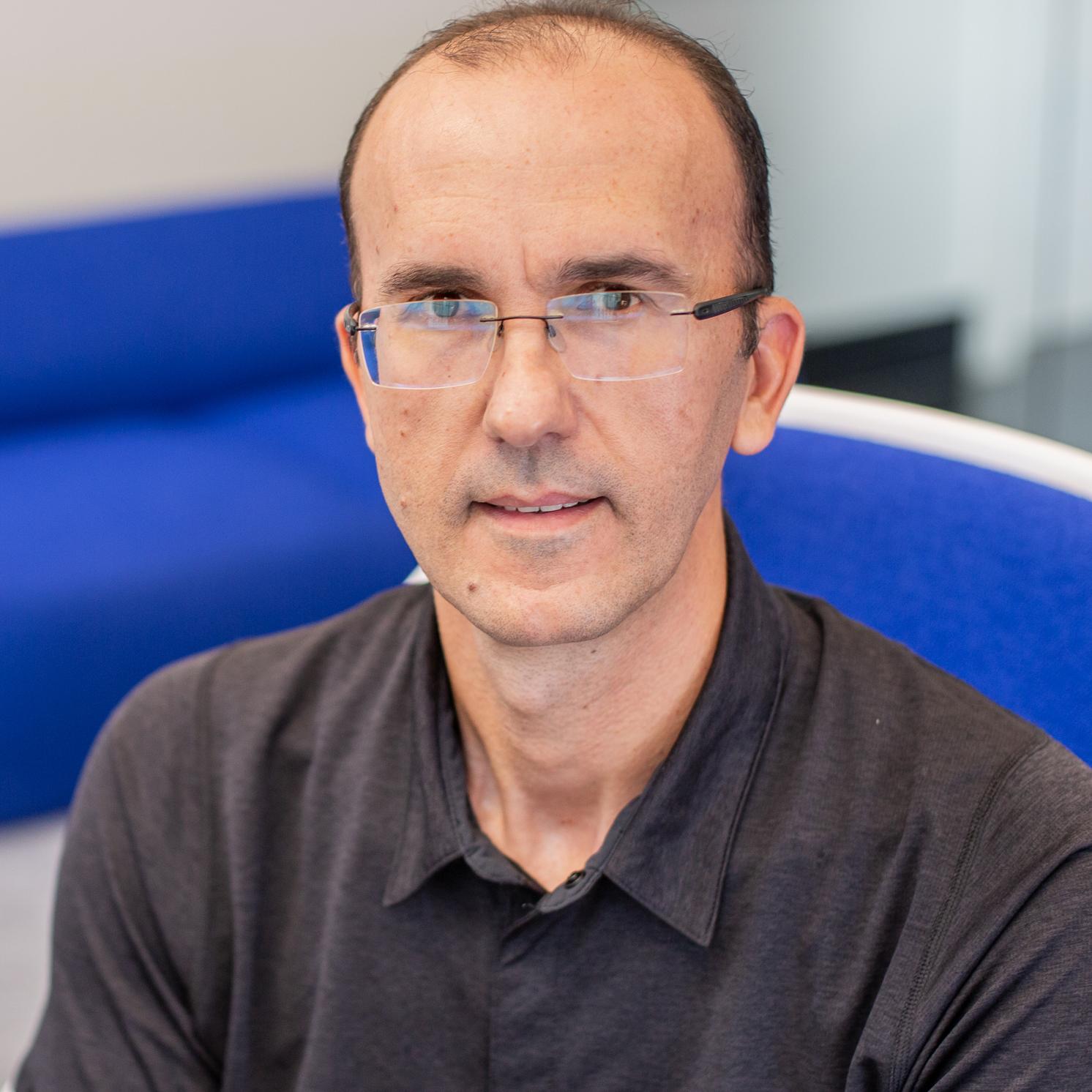 man wearing glasses sitting in a bright blue chair