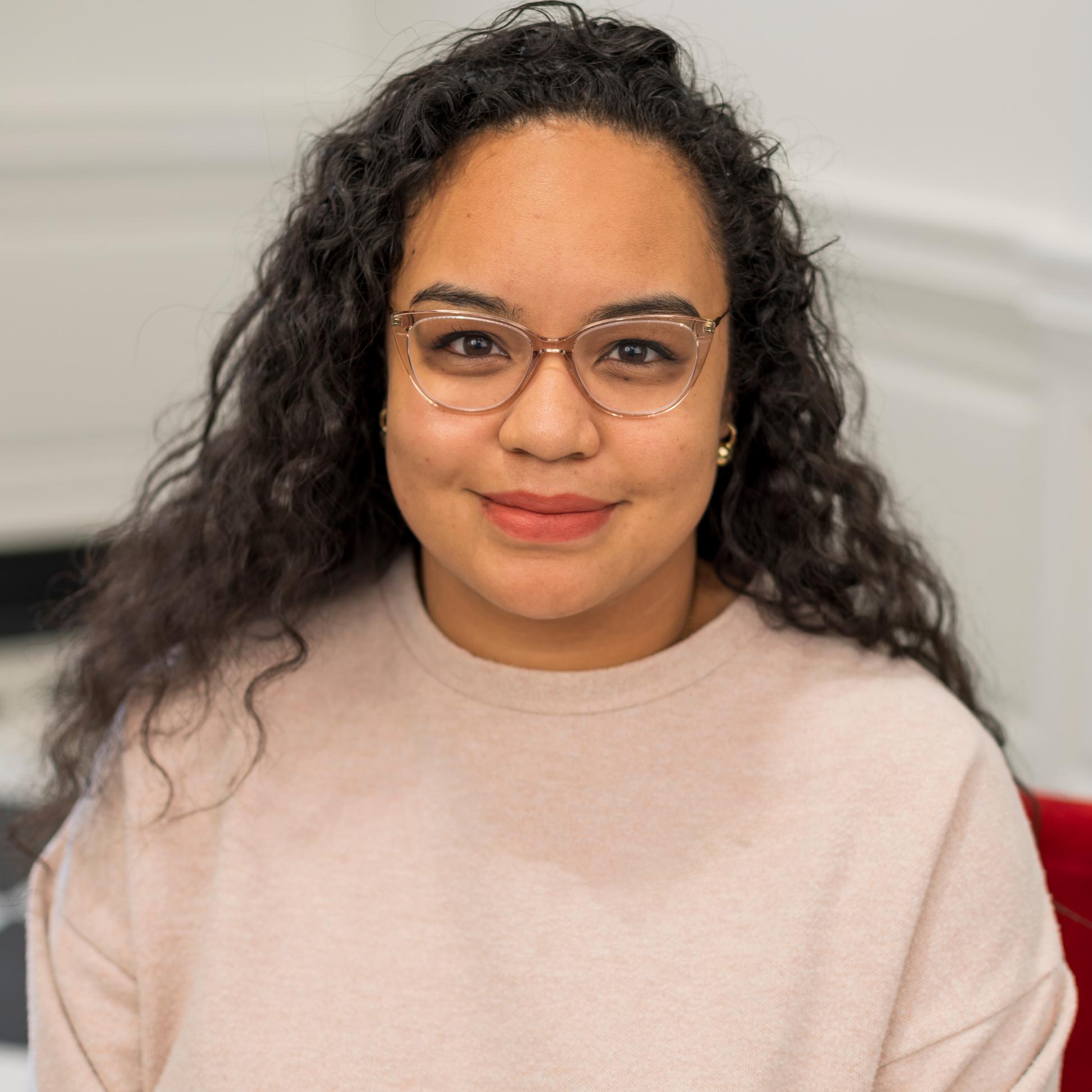 portrait of a woman wearing glasses sitting in a red chair