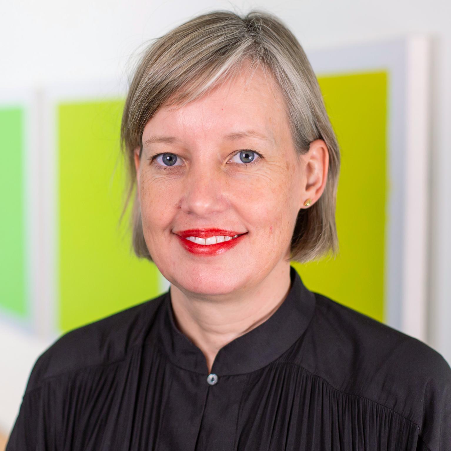 portrait of a woman standing in front of bright green panels