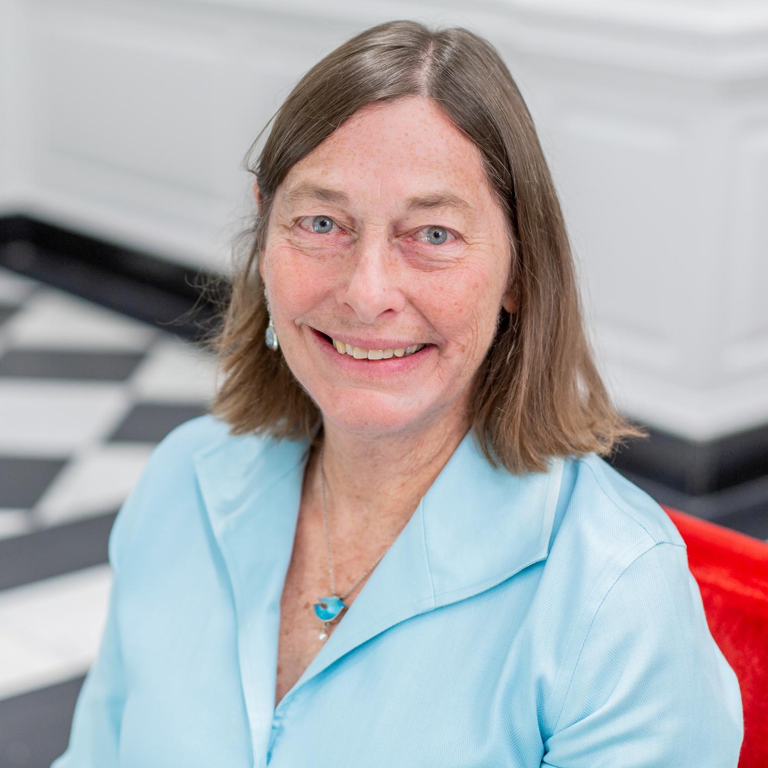 portrait of a woman in a light blue shirt sitting in a red chair
