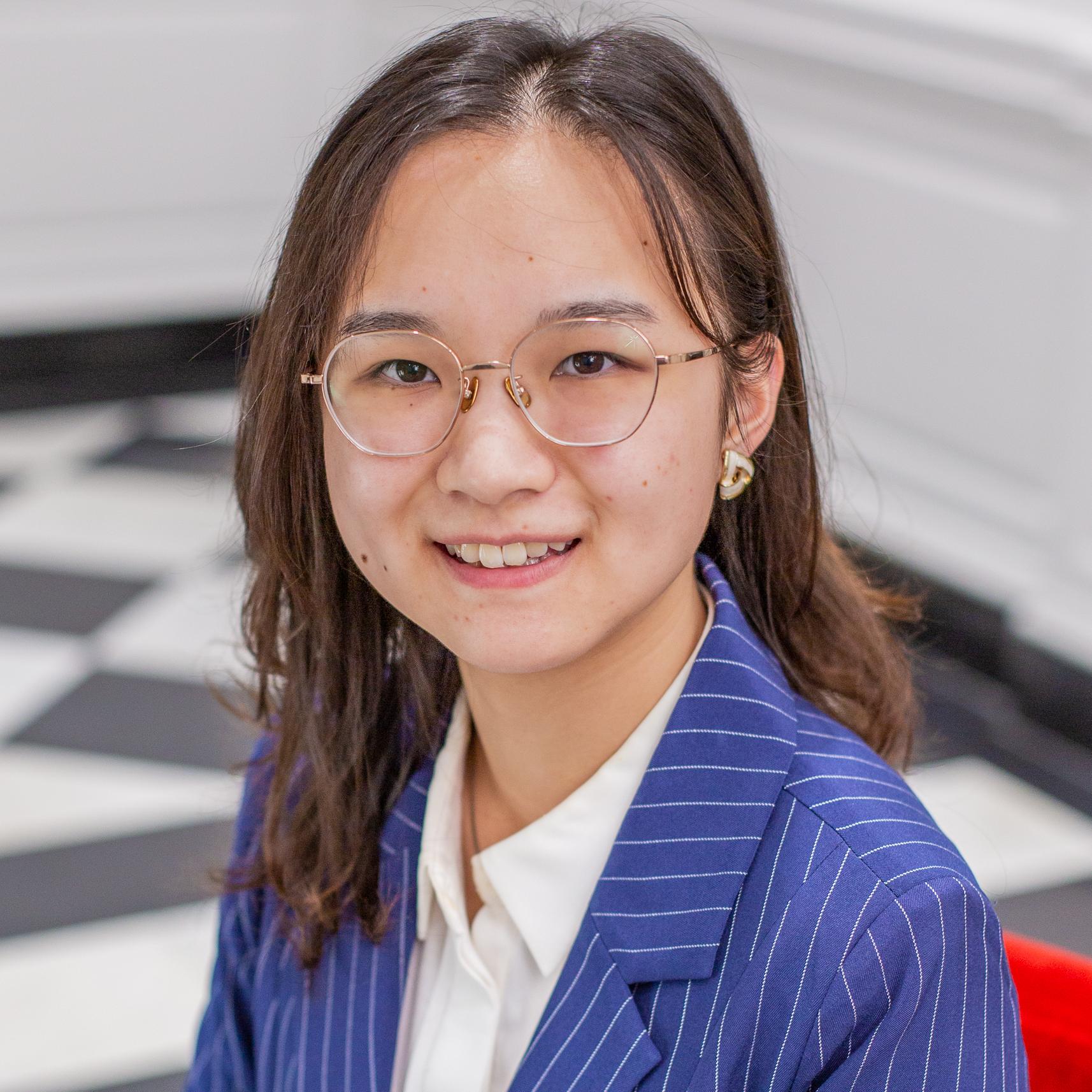 person with long brown hair and glasses wearing a blue blazer