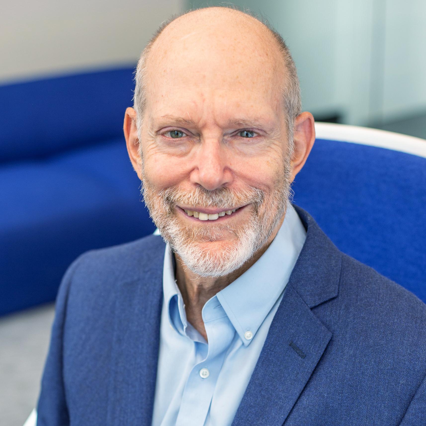 man in a blue suit sitting in a bright blue chair
