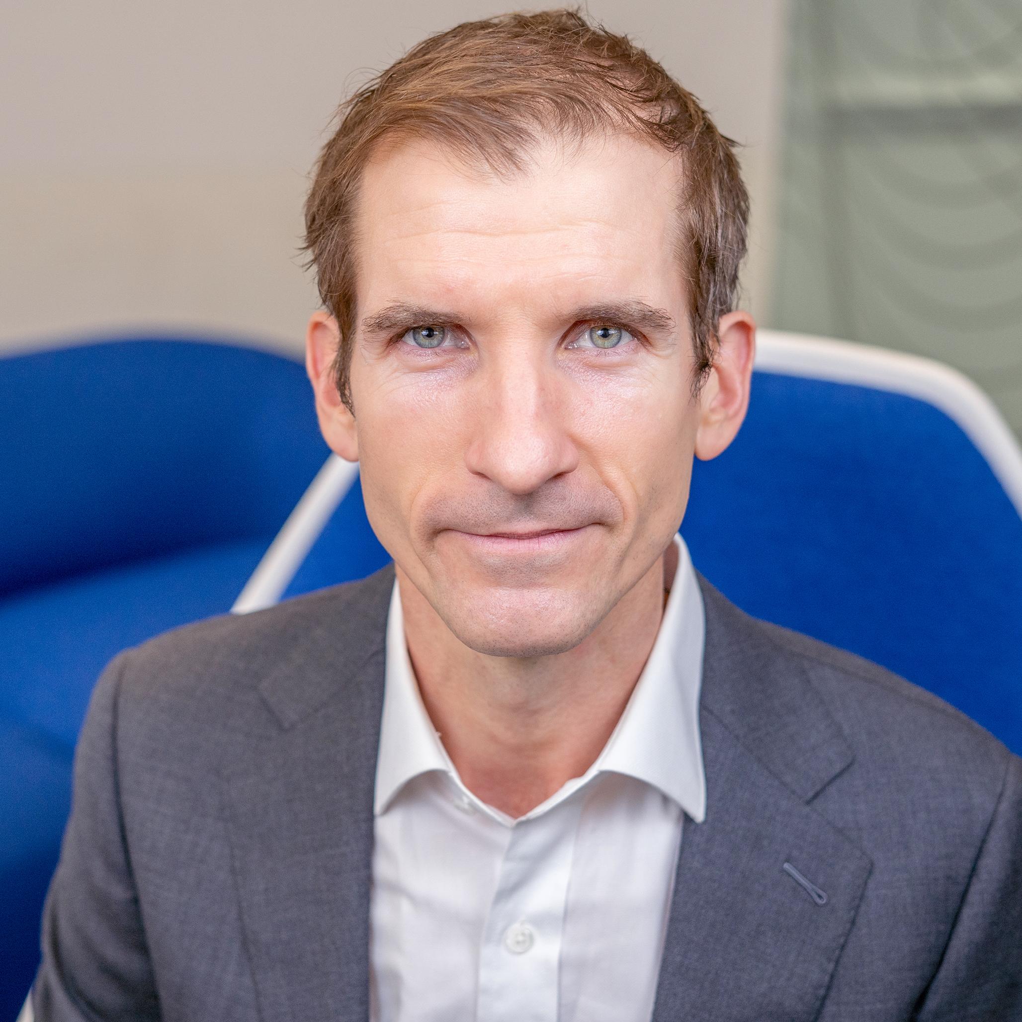man sitting in a blue chair looking at the camera