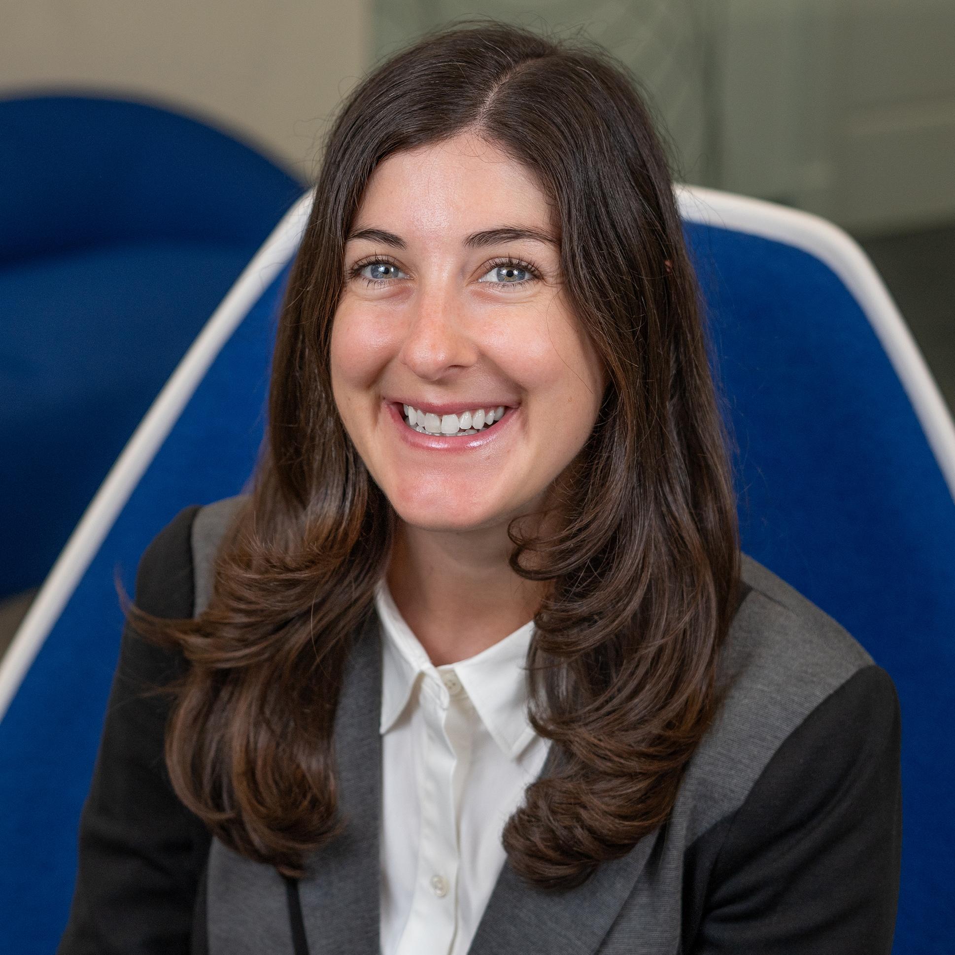 Woman sitting in a blue chair smiling at the camera