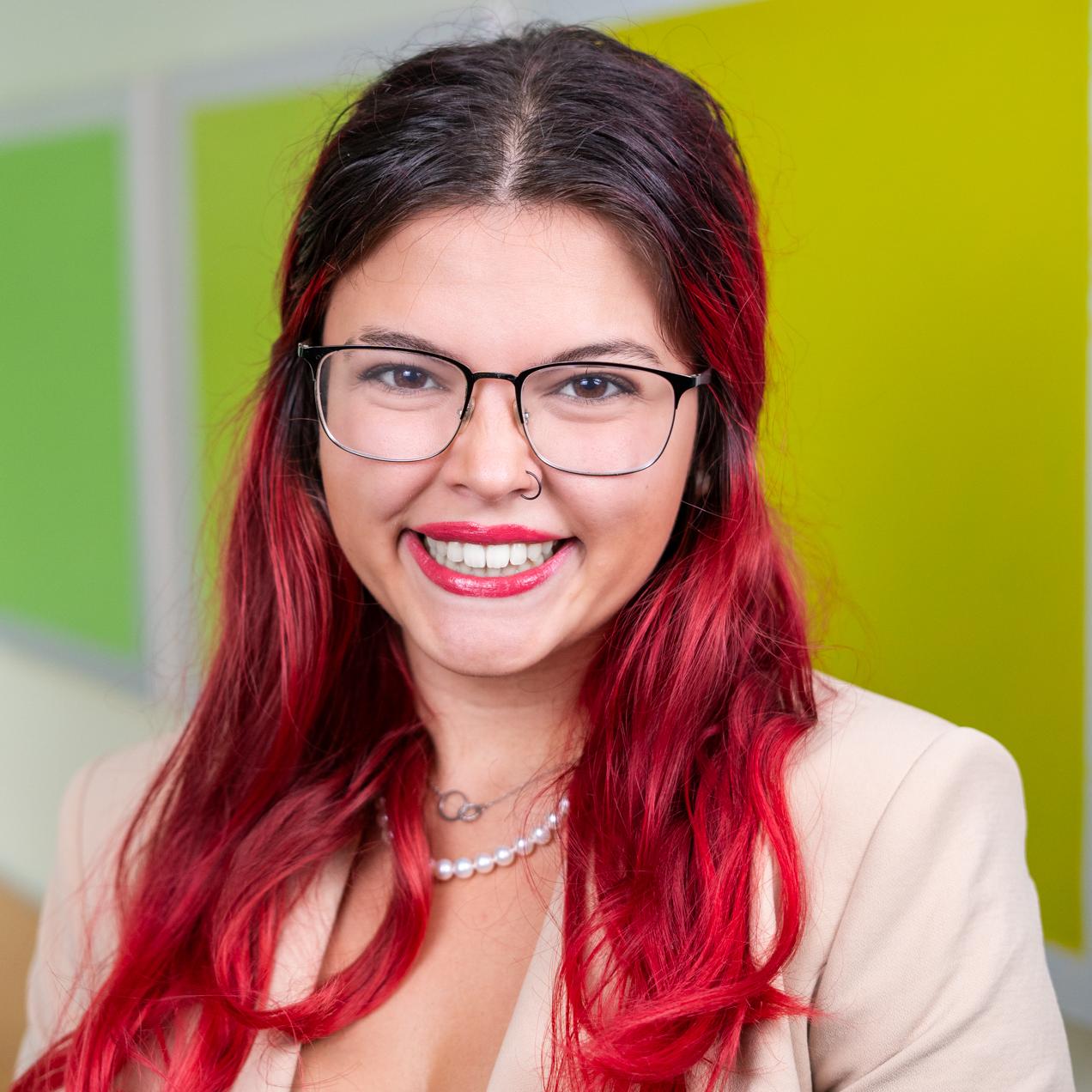 person with long red hair standing in front of bright green wall panels