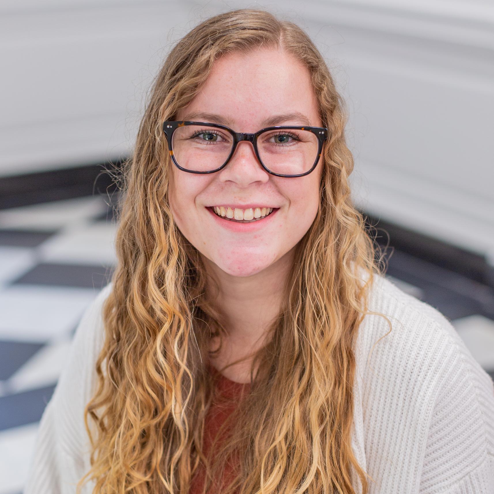 woman with long curly blonde hair and glasses