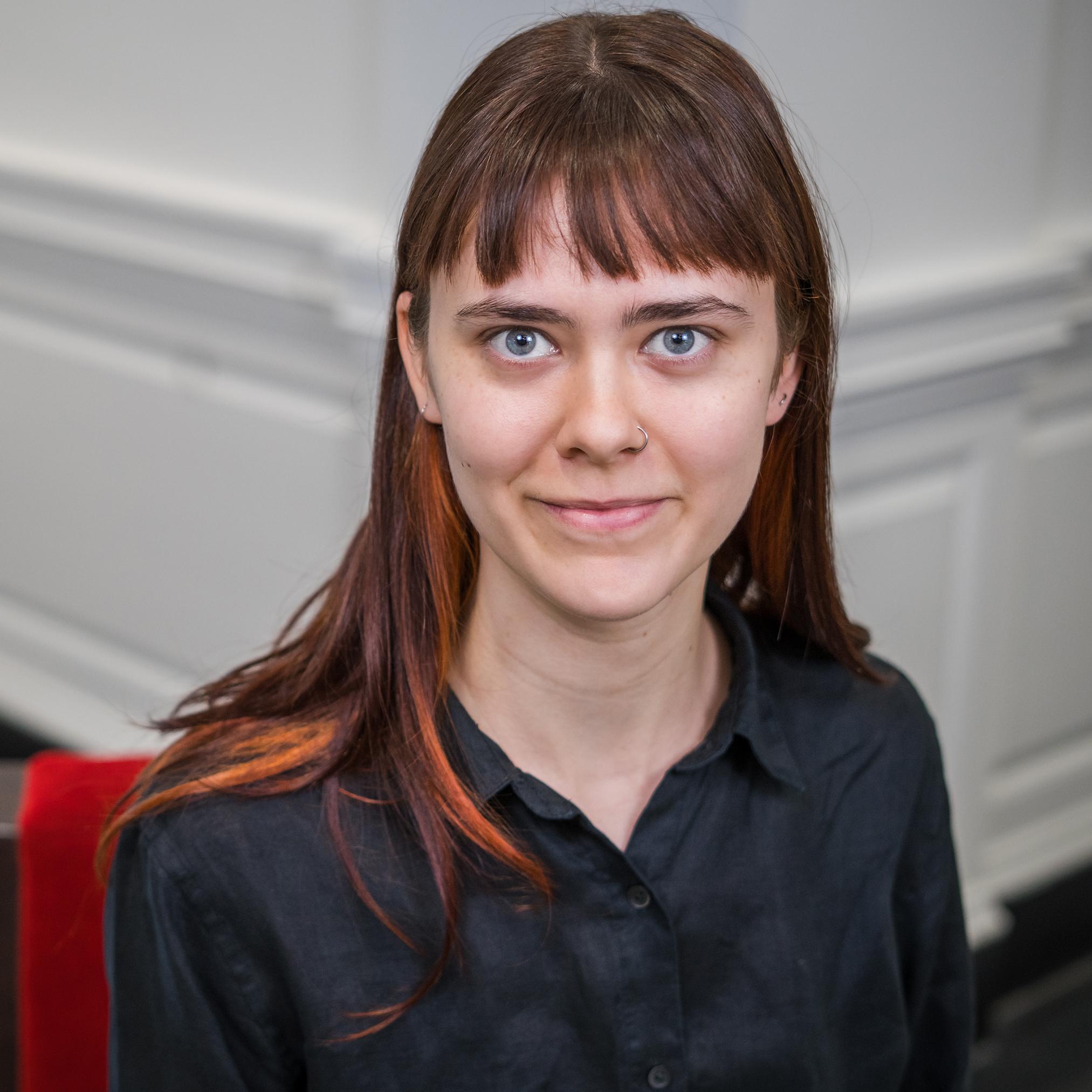 portrait of a person with long hair wearing a black button down shirt