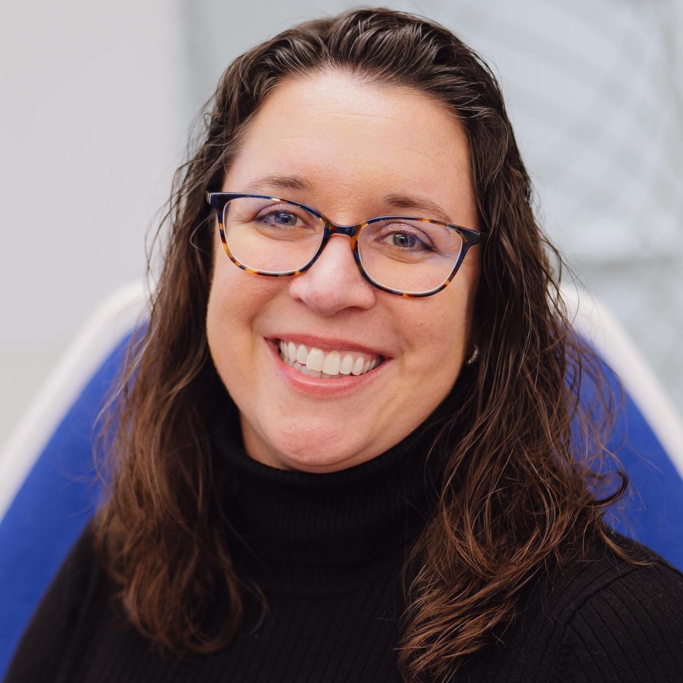 headshot of woman with brown hair and glasses
