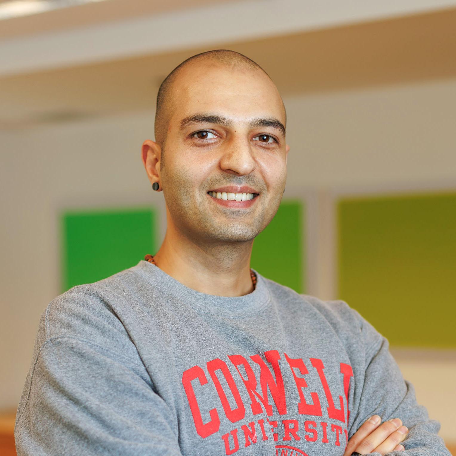 Portrait of Moji Ashour wearing a Cornell sweatshirt