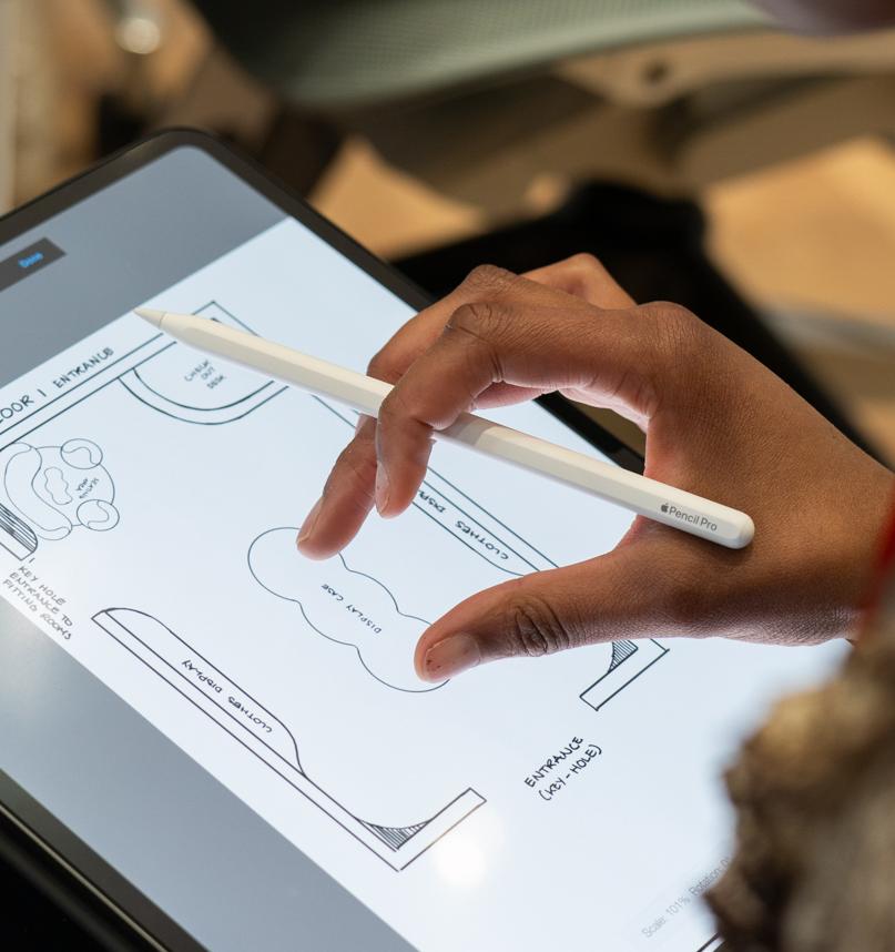 looking over the shoulder of a student working on a floorplan on a tablet