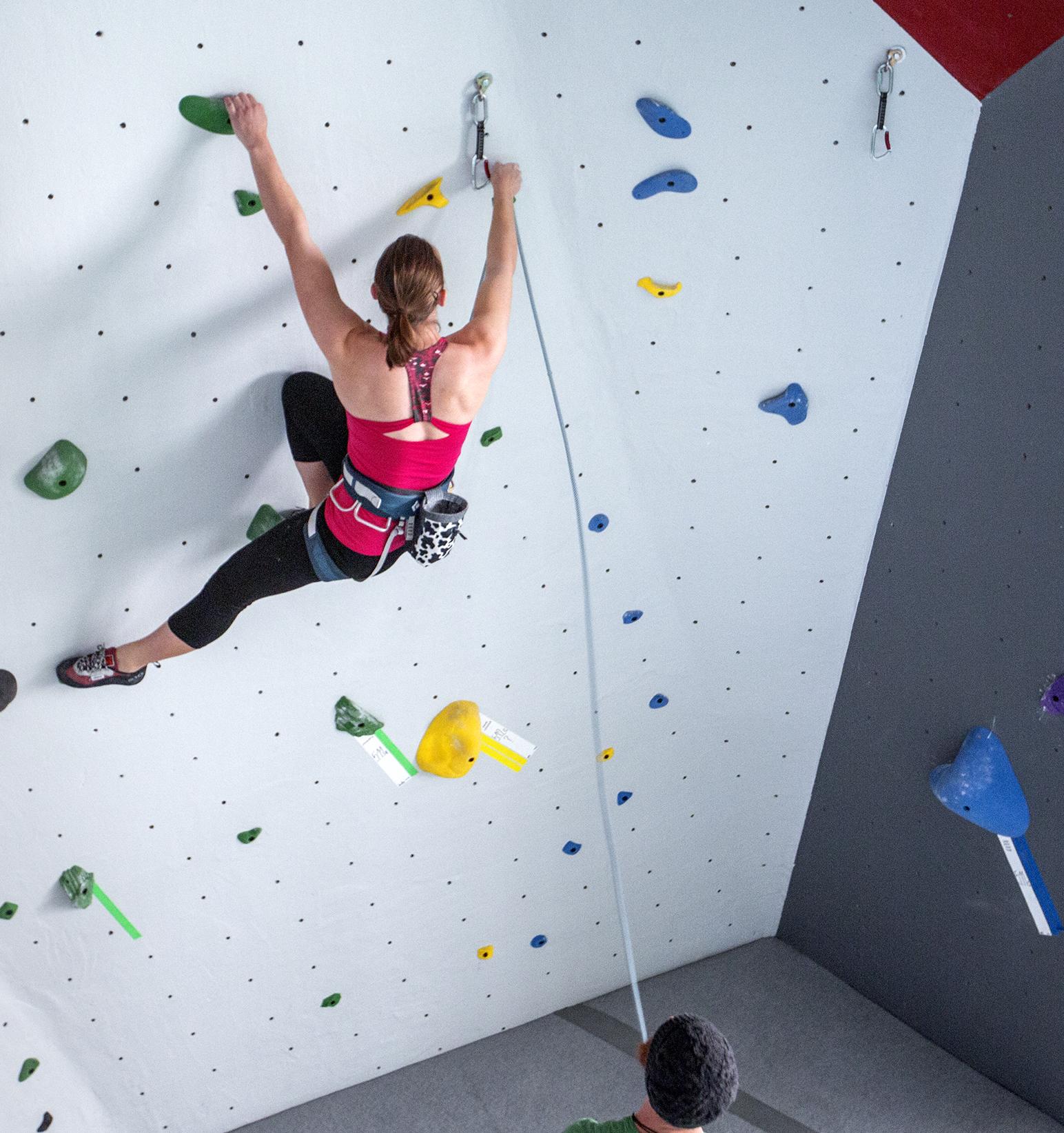 climber halfway up a large climbing wall