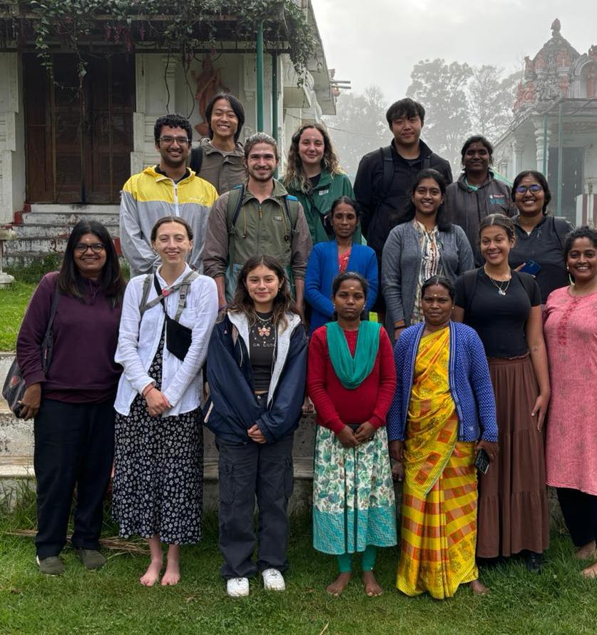 group of students stand with local people in India