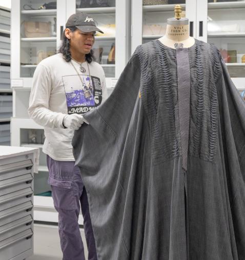 students and professor examine a caftan on a mannequin