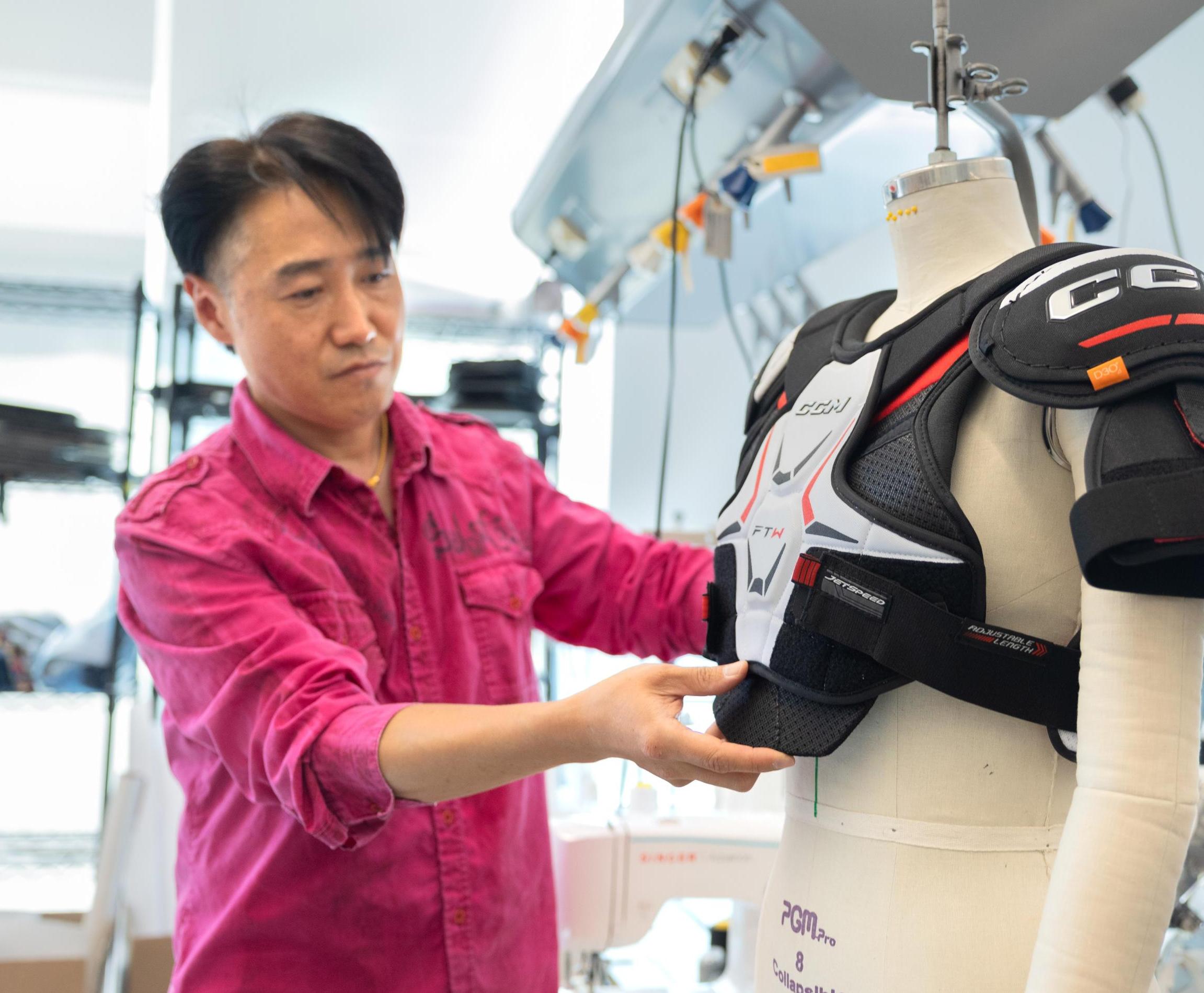 Heeju Park adjusts hockey protective gear on a mannequin