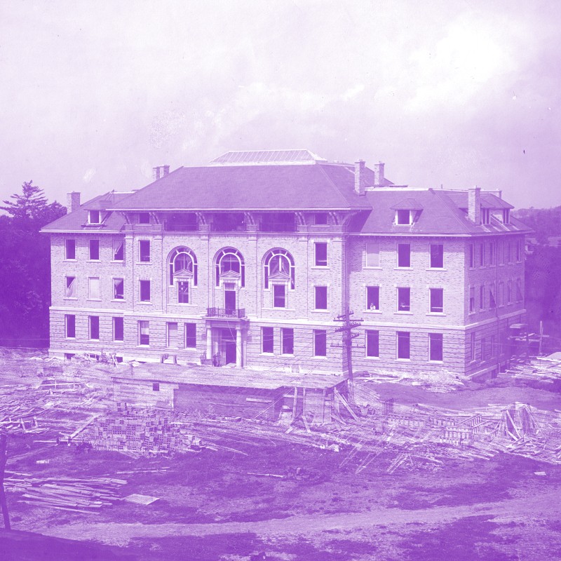 Building under construction circa 1912. Black and white photo with a purple wash