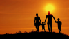 Family running on hilltop in sunset setting