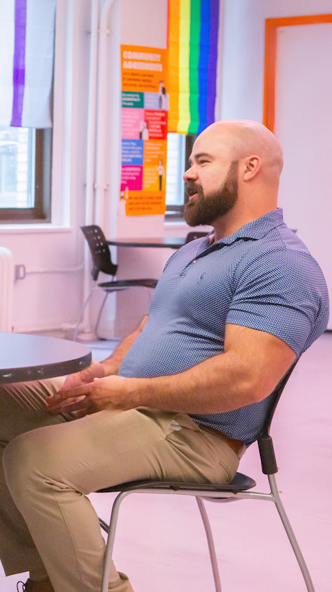 Adam Hoffman sitting in a chair at the Ali Forney Center